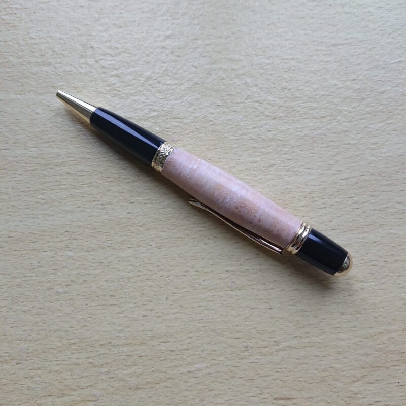 Handmade wooden pen from pale maple with broader width and black and gold colours to contrast against the wood. Retractable tip.