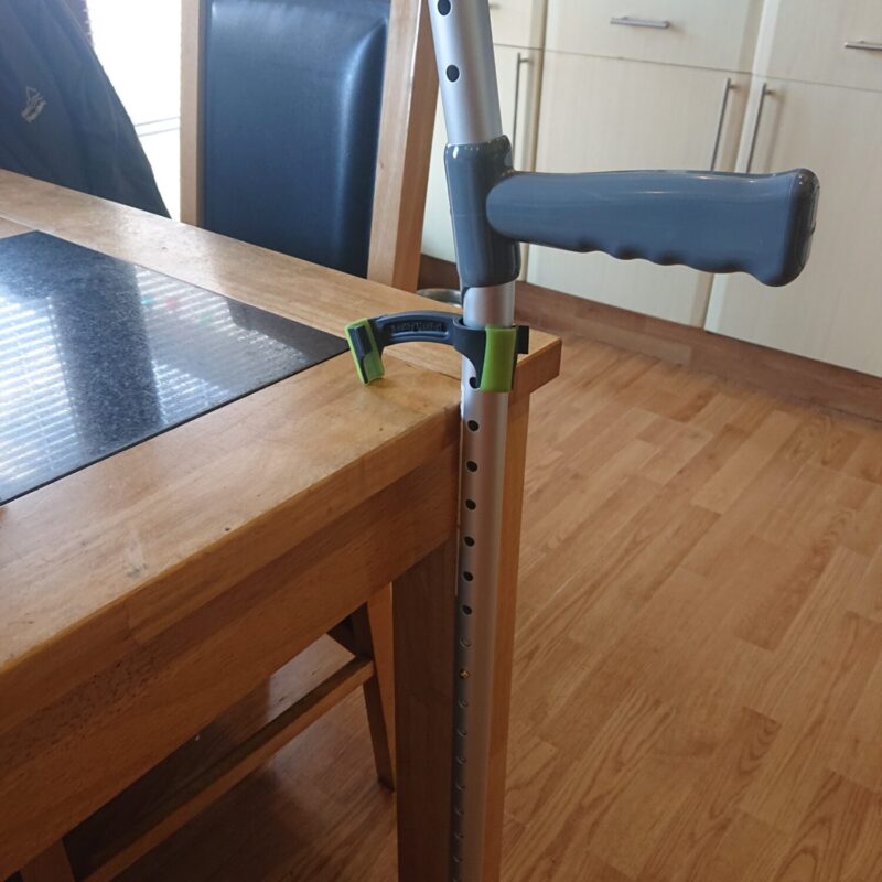 bridgit crutch and stick clip holding a crutch upright at the side of a dining table